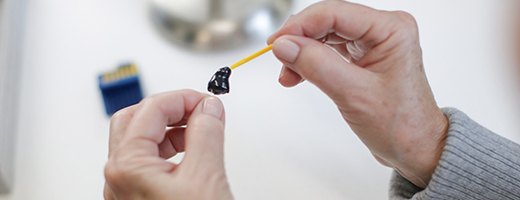 Image of a hearing aid wearer changing the wax guard on a custom hearing aid